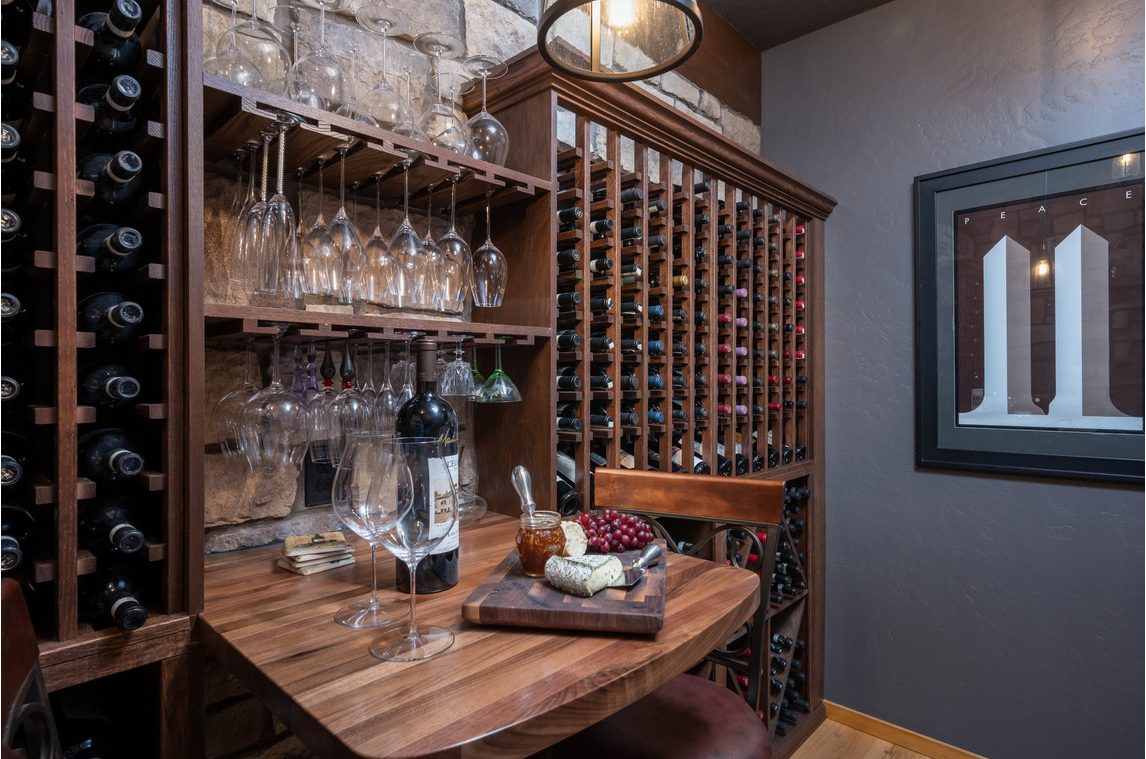 Custom wine cellar racking with stemware storage and walnut tasting table by Deschutes River Cabinet & Closet